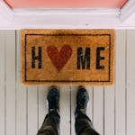 A creative doormat with heart motif symbolizing home at a front porch entrance.