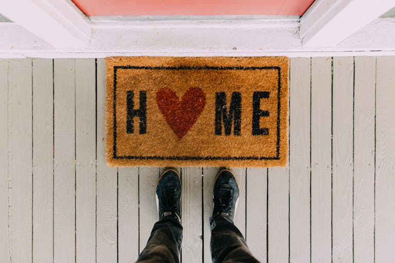 A creative doormat with heart motif symbolizing home at a front porch entrance.